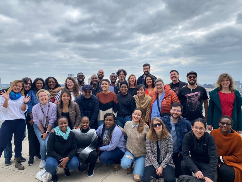 A group of Atlantic Fellows are posing outside under a sky of gray clouds.