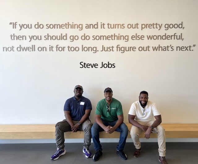 Three HBCUvc Fellows, including Nyland Sidifall, smiling in front of a Steve Jobs quote at Apple Park, the corporate headquarters of Apple Inc., located in Cupertino, California, United States.