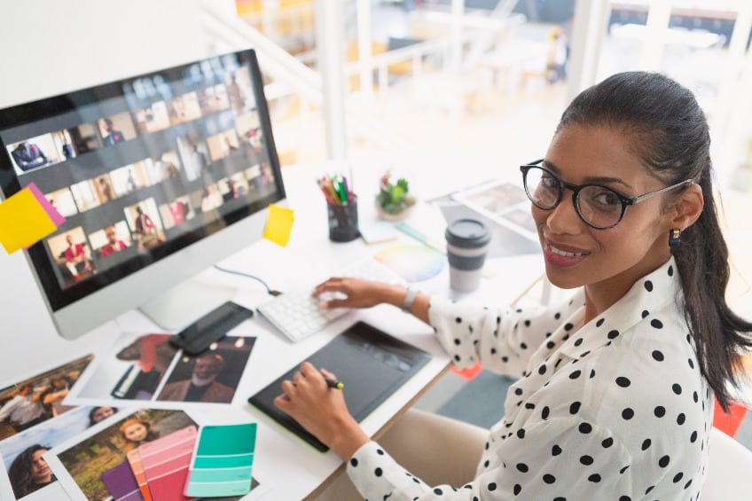 High angle view of happy mixed-race female professional working on her computer at a desk in office.