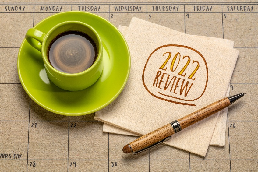 2022 review handwriting on a napkin with coffee and pen against desktop calendar, business still life concept