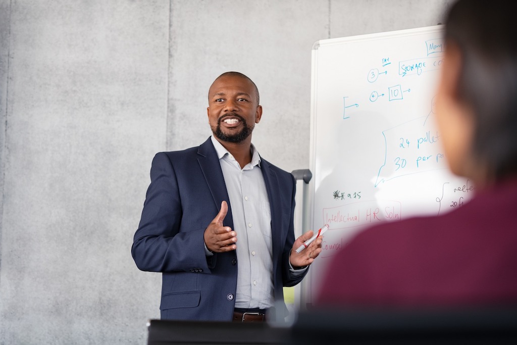 Male, African American professor presenting new concepts to business school students during a lecture.