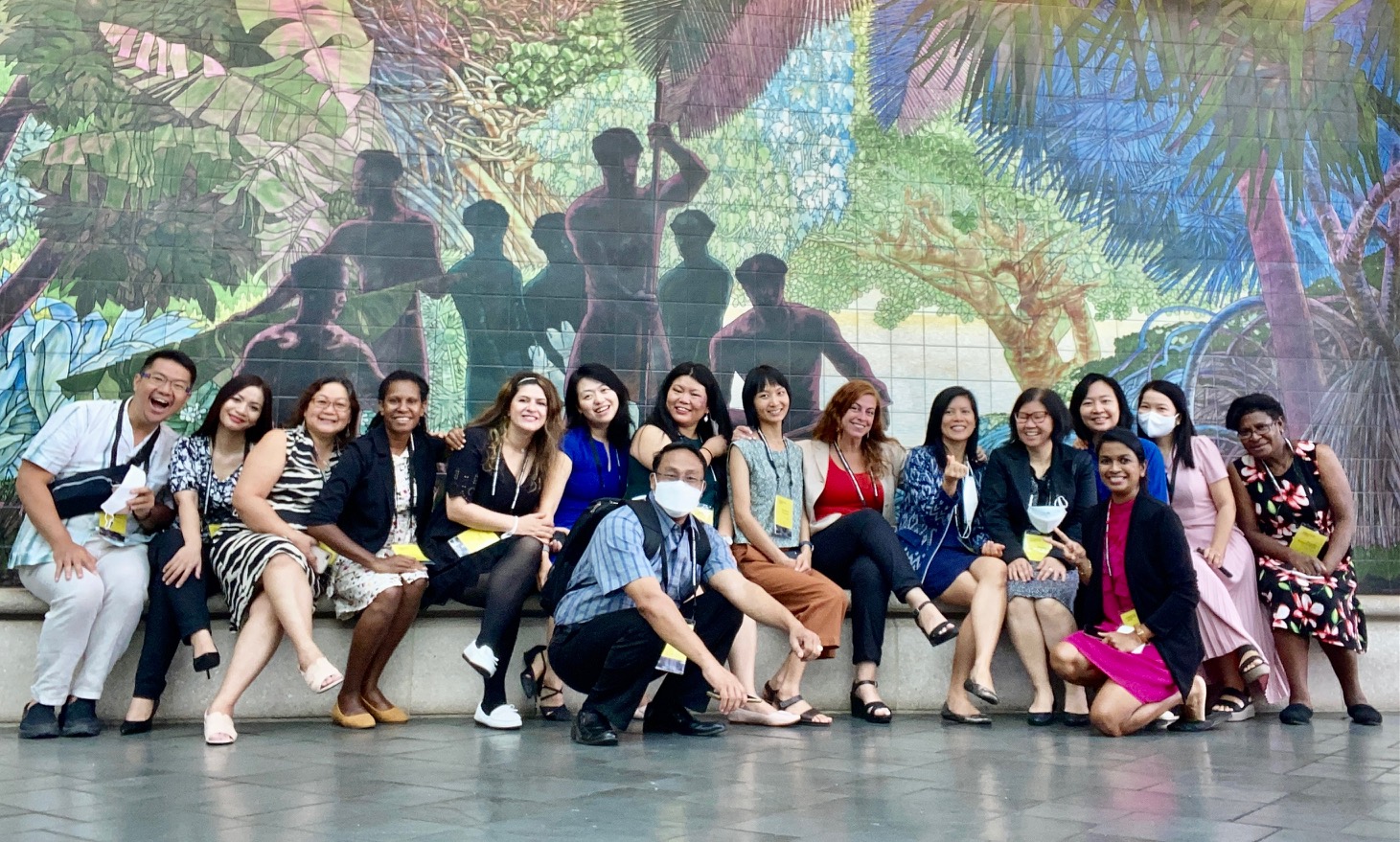 A group photo of the 2022 Asia Pacific Leadership Program Fellows smiling in front of a decorative jungle themed mural.