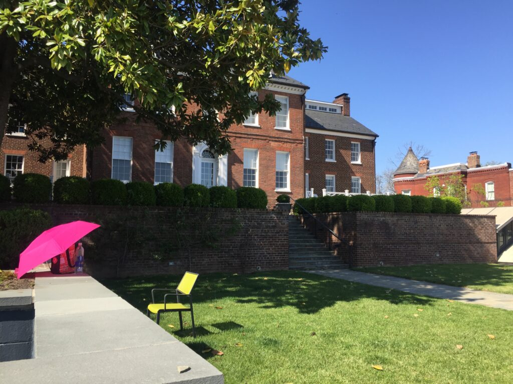 Halcyon yard green space on a sunny day with yellow chair and building in background.