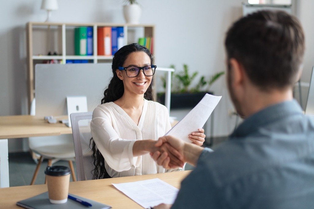 Smiling female graduate school applicant shaking hands with a professor