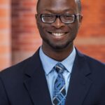 Ibitayo Ifeoluwa headshot in blue dress shirt and navy jacket.