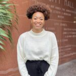 A professional photo of Juanita Gordon standing in front of a marble wall outside of City Hall in New York City.