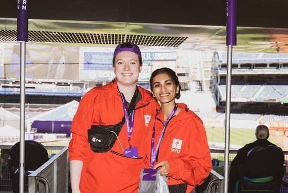 Nisha Shankar, who is pursuing a fully funded master's degree at NYU, posing for a picture alongside another NYU employee while volunteering at the NYU Commencement at Yankee Stadium in May 2022.