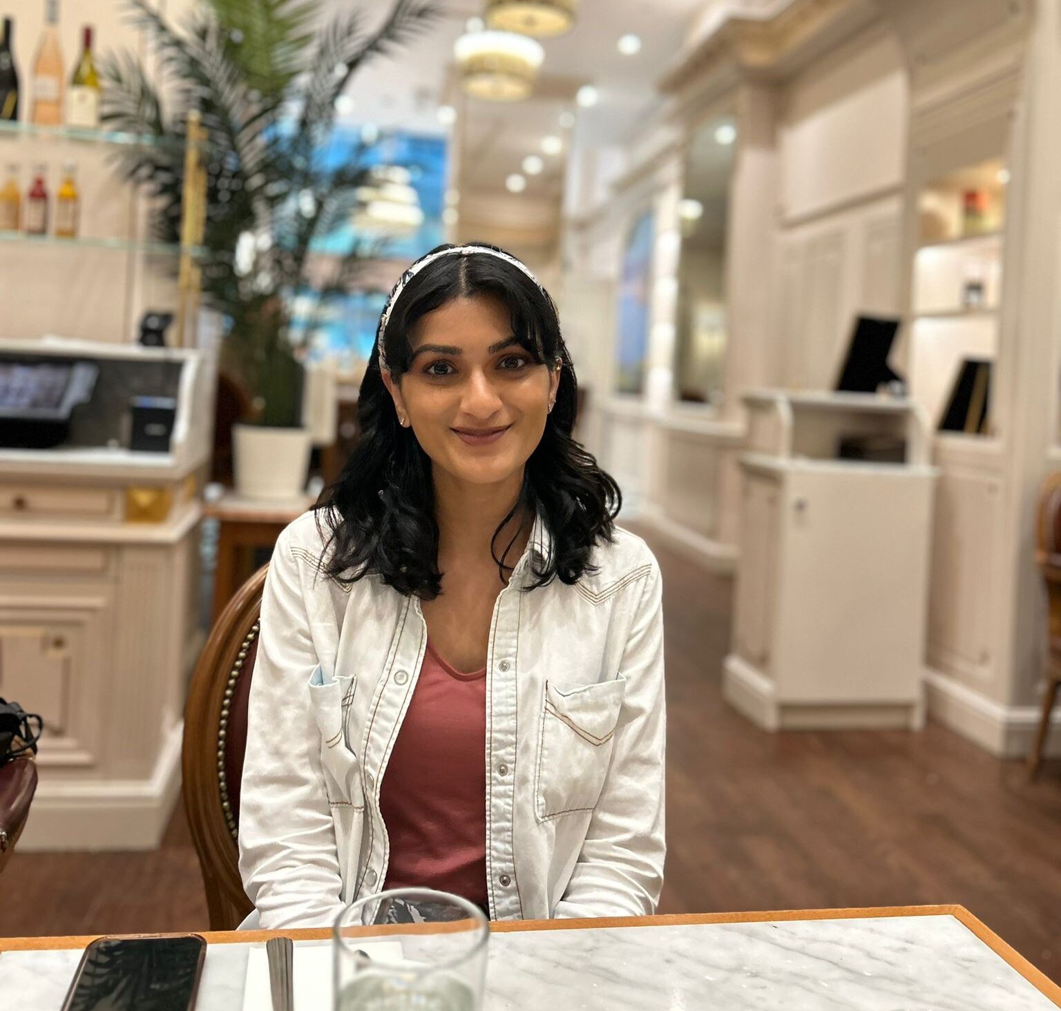 Nisha Shankar, a full-time NYU employee pursuing a fully funded master's, sitting at a table about to enjoy a meal while visiting the United Nations Headquarters on a class trip.