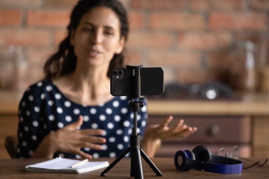 Young hispanic woman recording a video using her mobile phone for her fellowship applications.