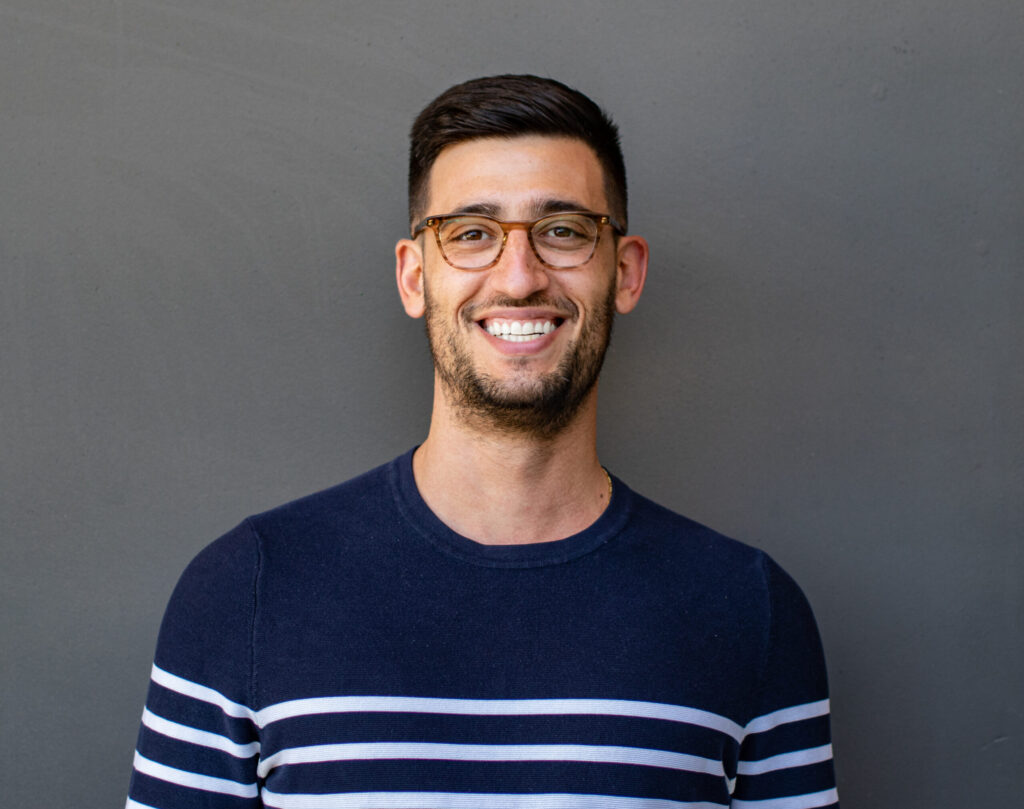 Dan Egol, a 2023 Roddenberry Fellowship winner, smiling for a professional portrait in front of a dark grey backdrop.