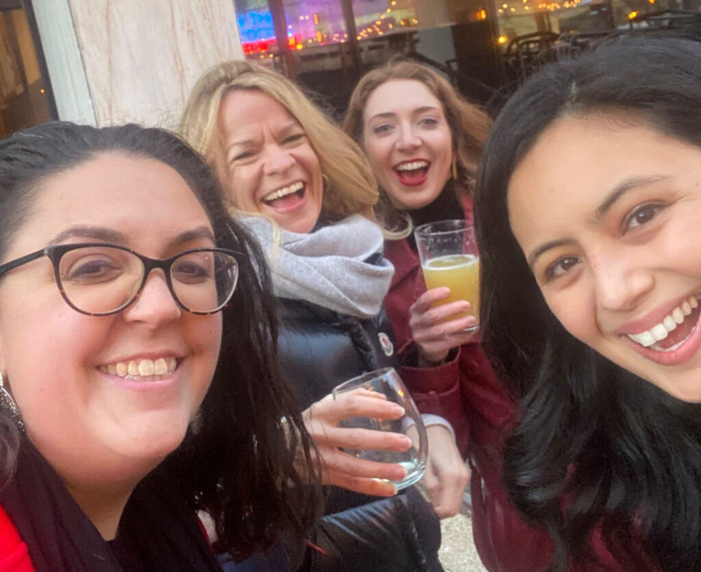 A group of women accepted into the Presidential Innovation Fellowship smiling and holding drinks outside.