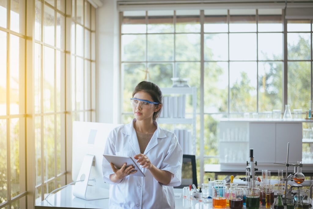 Beautiful young asian female chemist working on her Fulbright research project in a laboratory and recording findings on an iPad.