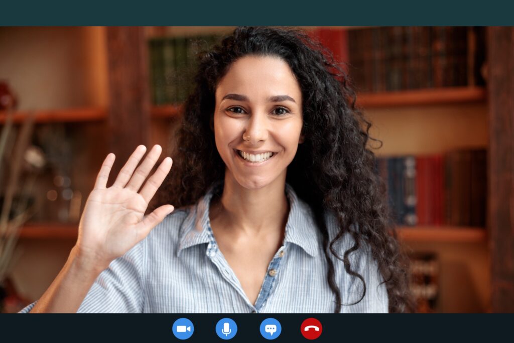 A smiling young female graduate student waving her right hand to say hello to her cohort of fellows who are participating in remote fellowships for graduate students.