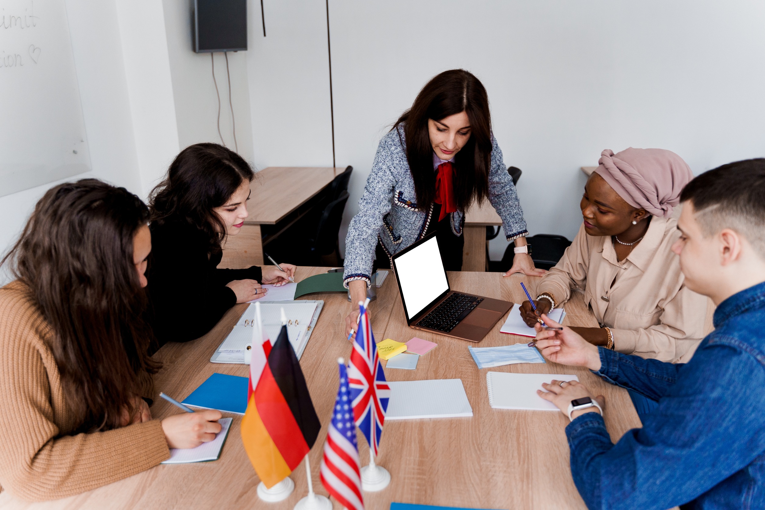 A language instructor works with a group of multicultural students after earning her degree from one of the Fully Funded Master's Programs in Linguistics