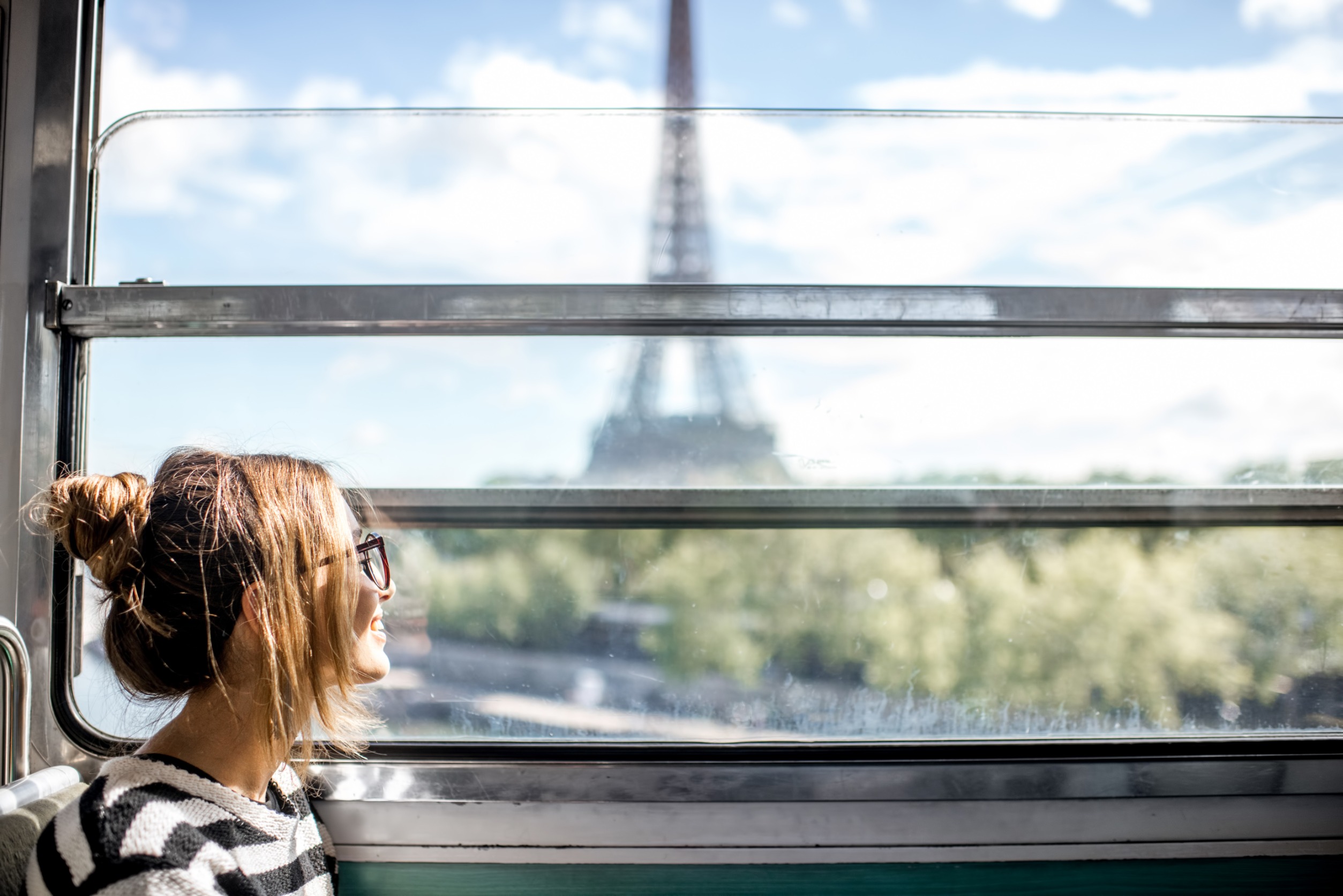 A woman smiles on the train in Paris where she uses the skills gained at one of the Fully Funded Master's Programs in French and Francophone Studies.
