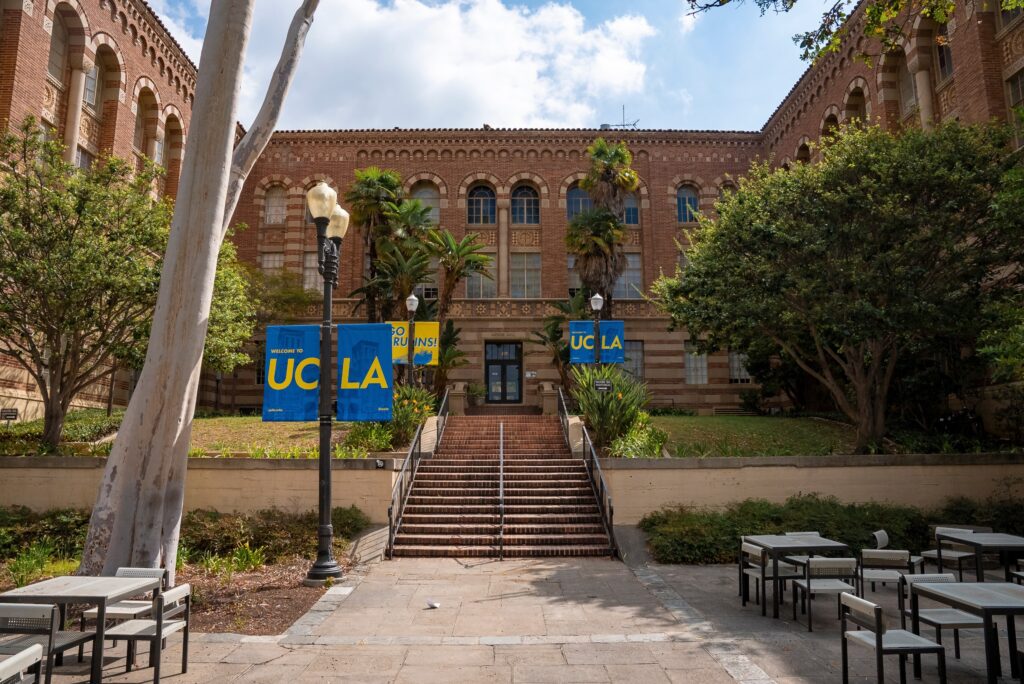 Steps towards the entrance of a building at UCLA with posters on streetlights on campus