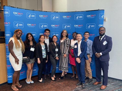 Darnell Davis, far right hand side, standing with his Rise Fellowship cohort. The group consisting of 10 people are standing in front of a large, blue, CDC banner