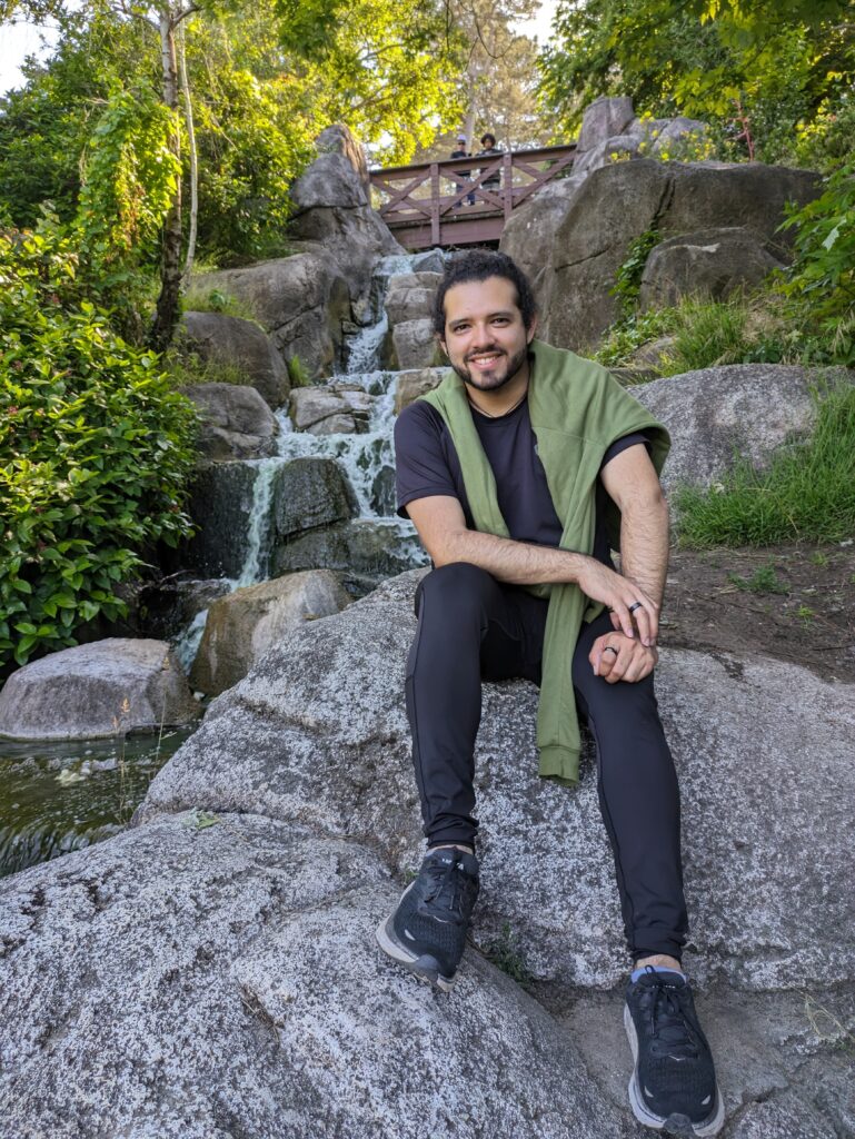 EDF Climate Corps Fellow Daniel González sitting on rocks in front of a small water fall in Golden Gate Park, San Francisco.