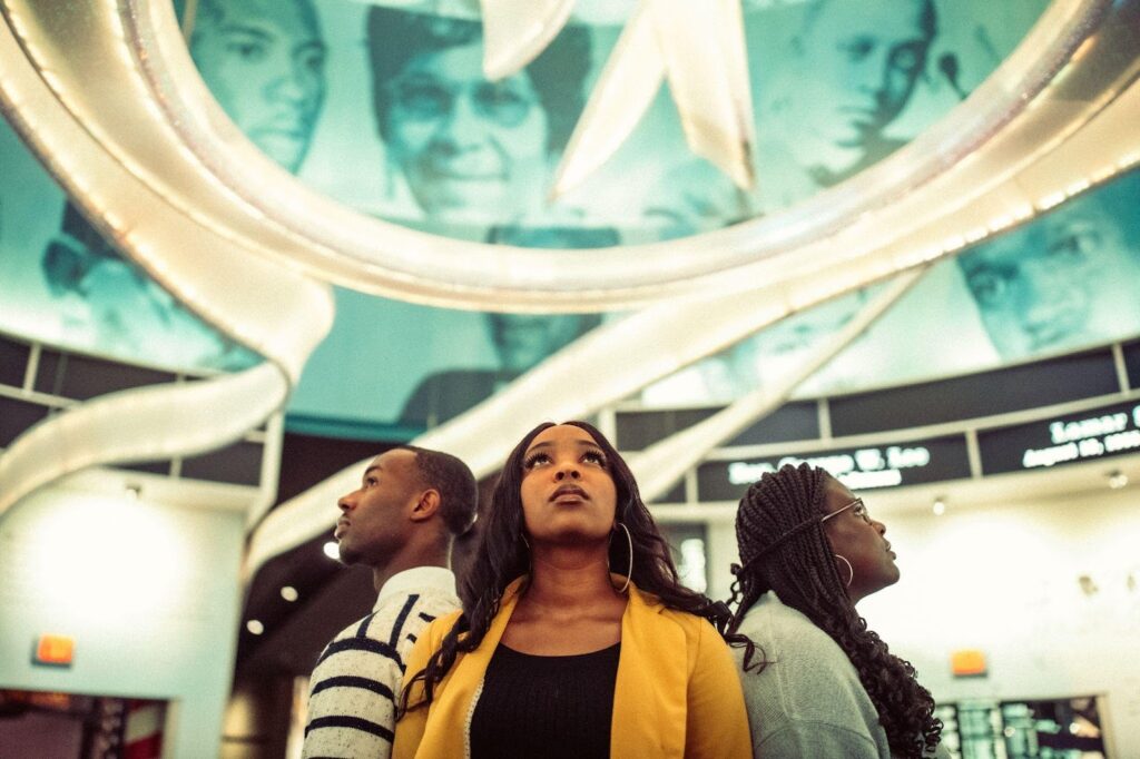 Cover image for the Fellowship Alumni Network (FANS) report which shows three black young professionals standing back to back in the center of a hall looking outward. The FANS report was created in partnership with IREX and the W.K. Kellogg Foundation.