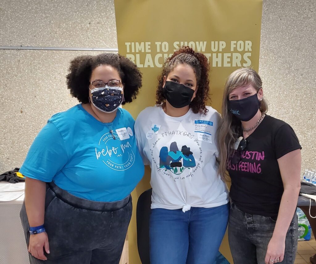 Global Health Corps Fellowship winner Paris Acosta, center, with her sister Michelle, on the left, and friend Rachel Stone, on the right. They pose in front of a yellow banner .