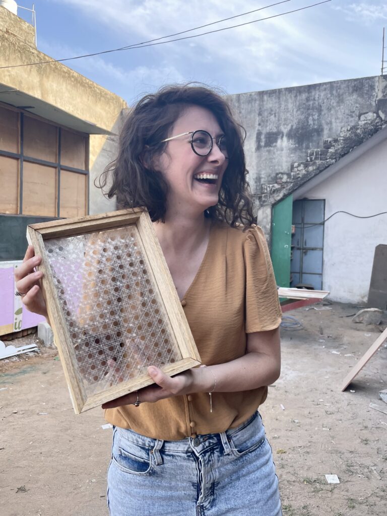 Erin Burneson, smiling and facing away from the camera, holds a hosting tray handwoven from single use plastic water bottles.