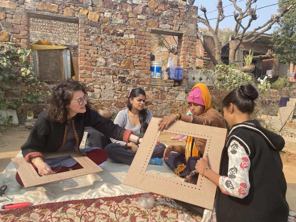 A group of four people, including Erin Burneson, during the Banyan Impact Fellowship, on the left, sits cross-legged on the floor holding square wooden frames during a fellowship activity.