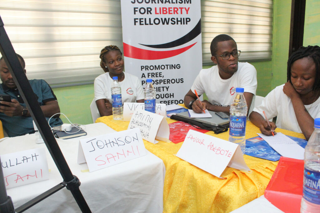 Favour, Victoria Jooda and Muhammad Adeyemi sit at a corner table with name tags listening avidly.