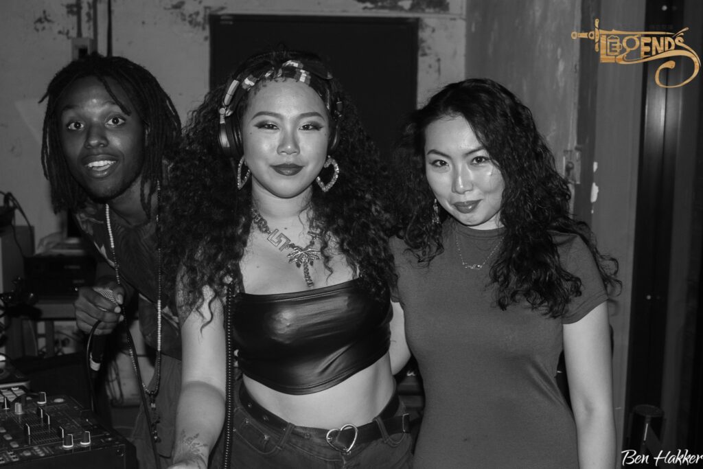 Miles, smiling, standing next to a DJ artists and another woman at Legends Sports Bar in Tainan. The image is in black and white.