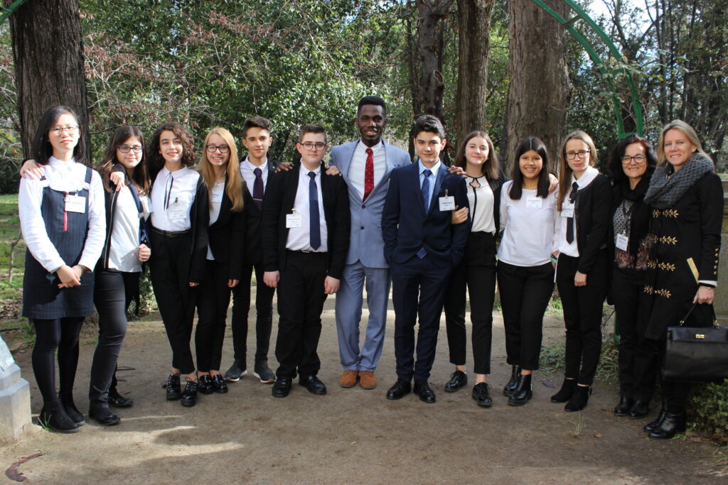 Olugbenga stands with a group of Spanish students in a forest in Spain.