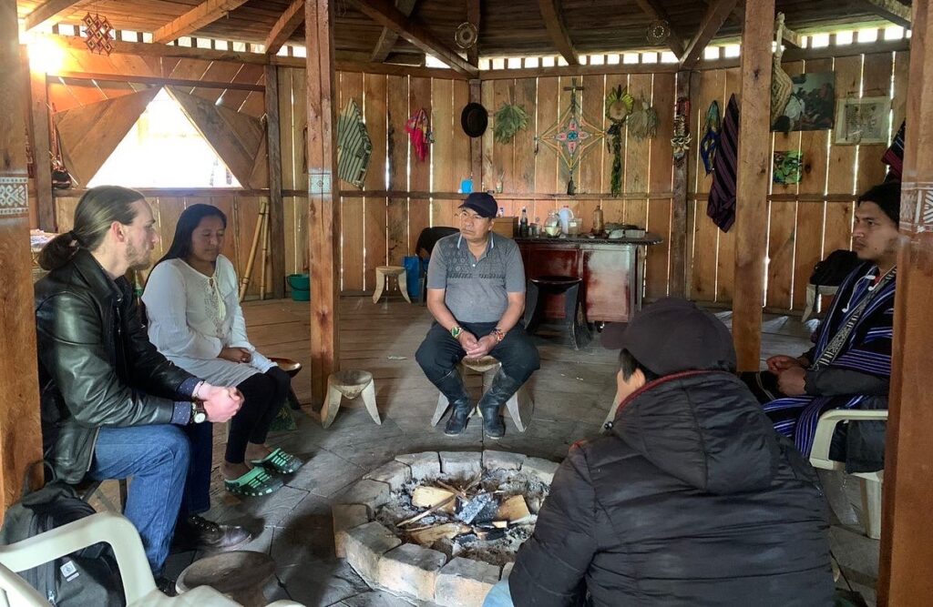 Rowan Glass, interested in anthropology, interviews people around a fire put in Colombia.