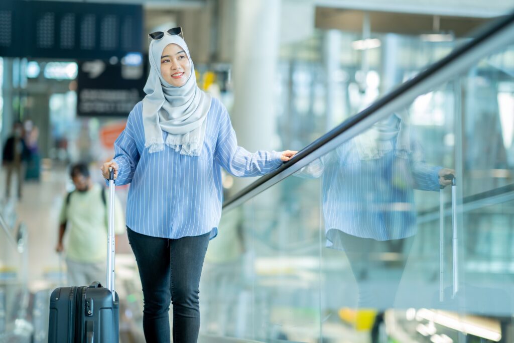 Young Muslim Woman wearing a headscarf or hijab, walking with luggage in an airport for her Fulbright Scholar Award Trip