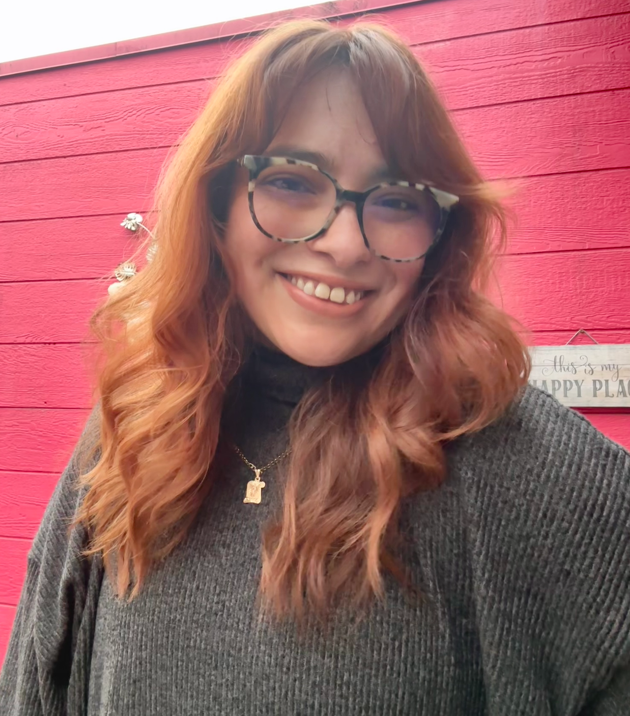 Headshot image of postdoc, Dr. Valencia. She is wearing a gray sweater and glasses.